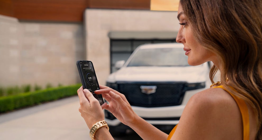 lady checking her mobile with a Cadillac vehicle background | Bentley Cadillac Huntsville in Huntsville AL